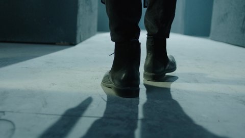 Close up of male legs in black boots.  Rear back view of man walking inside dark maze. Man walking inside dark room, corridor. Footage of mystical video. Shot on ARRI ALEXA Cinema Camera slow motion