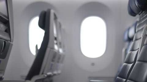 Empty row of dark blue seats inside an airplane with windows as background. Peaceful and tranquil interiors of commercial plane. Means of transport
