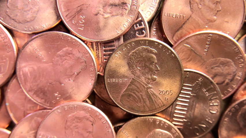 4K HD video zooming in on one coin in the middle of a pile of pennies. Pennies were the first coins minted in the U.S. and there have been 11 different designs featured on them.
