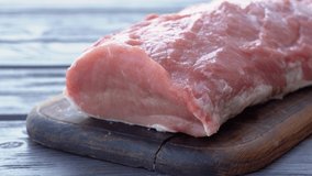 Closeup view 4k video of fresh pork meat laying on wooden board on brown table background