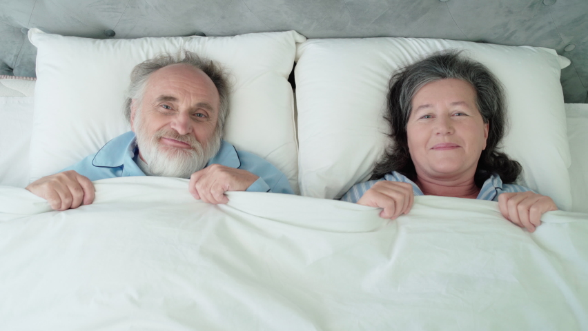 Happy mature couple lying in bed, covering with blanket, romantic relationship Royalty-Free Stock Footage #1065422959