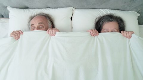 Happy mature couple lying in bed, covering with blanket, romantic relationship