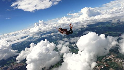 Image of a woman parachutist in casual clothing smiling and having fun in free fall. Recorded in slow motion in 4K definition.