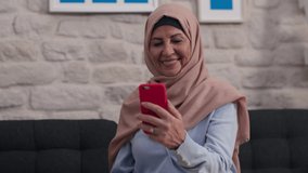 Old woman in turban is having a video conversation with her mobile phone in slow motion. The old woman with a turban is having a video chat with her loved ones at home.
