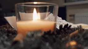 Close-up of a candle in a glass. Beautiful Christmas table with ingredients for Christmas cookies. Flour in a bowl. A beautiful wreath is made of spruce.