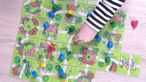 4k Board game and kids leisure concept - kids hands playing wood chips people figure in children table top game carcassonne - 11 jan 21 St.Petersburg Russia.