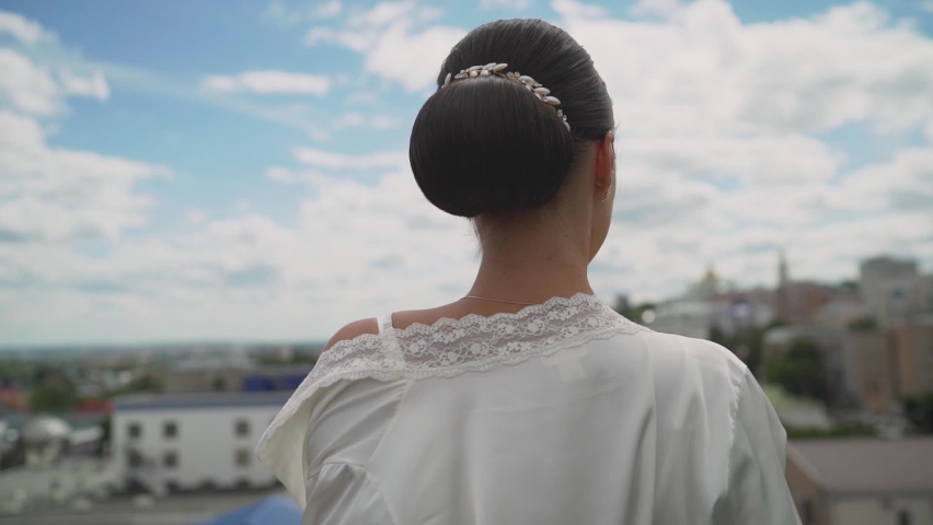 Girl in a white robe on the roof of the hotel. Young brunette in a light robe and sunglasses.