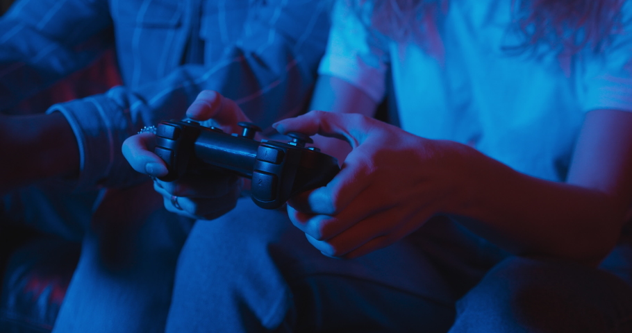 Young man and woman are playing video games together using controllers. Red and blue neon lighting. Royalty-Free Stock Footage #1065456631