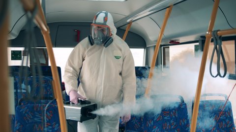 A disinfector sprays a bus during coronavirus pandemic.
