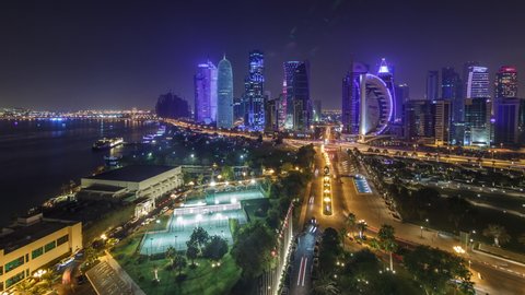 The skyline of the West Bay area from top in Doha timelapse, Qatar. Illuminated modern skyscrapers aerial view from rooftop at night. Parks and traffic on the road