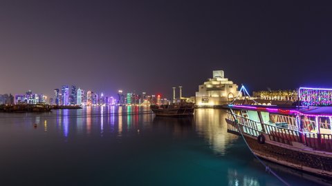 A panoramic view of the old dhow harbour night timelapse hyperlapse in Doha, Qatar, with the West Bay skyline in the background. Modern skyscrapers and museum on background and old boats on foreground