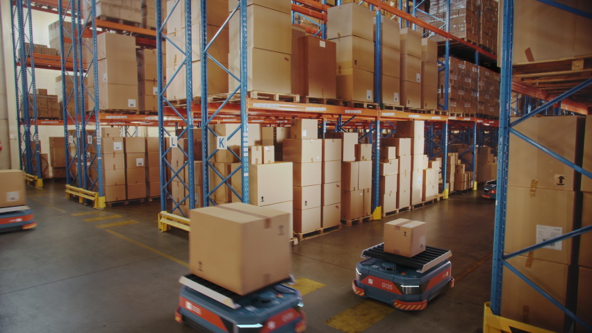 Future Technology: Automated Modern Retail Warehouse Delivery AGV Robots Transporting Cardboard Boxes in Distribution Logistics Center. Automated Guided Vehicles Delivering Goods, Products, Packages