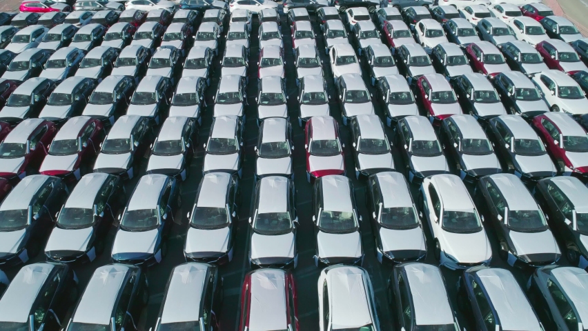Aerial view of new cars parked in car parking lot. Car dealer parking lot full of new automobiles. New cars lined up for import and export business. Royalty-Free Stock Footage #1065474100