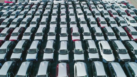 Aerial view of new cars parked in car parking lot. Car dealer parking lot full of new automobiles. New cars lined up for import and export business.