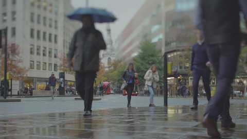 Streets of London and pedestrians walking in a rainy fall day, tilt-shift lens blurs faces
