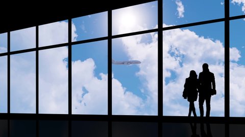 The silhouette of a couple standing in the observation area of an airport, watching a commercial airplane taking off and getting airborne.