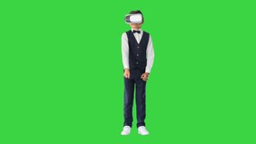 Excited boy in formal wear playing the sword game in virtual reality goggles on a Green Screen, Chroma Key.