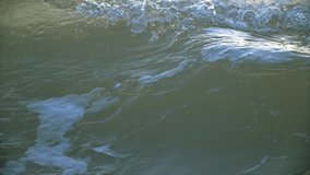 This slow motion video shows a close up view of rough ocean waters transitioning to calm, flowing waves.