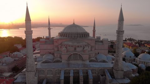 Establishing aerial drone shot of a Hagia Sophia Holy Grand Mosque (Ayasofya Camii) with Bosphorus and city skyline on the background in Fatih, Istanbul, Turkey at sunrise