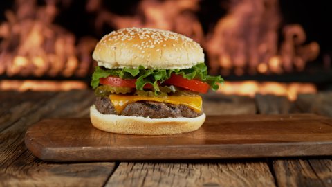 Hamburger on wooden surface with flames in background. Shot on Phantom Flex 4K camera.