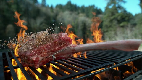 Tomahawk steak falling onto grill in slow motion. Shot with Phantom Flex 4K camera.
