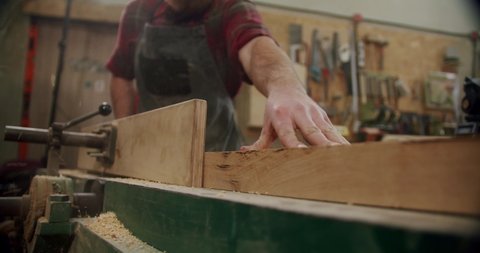 The master cuts a wooden board with a circular saw in the woodworking workshop of a small furniture manufacturer. Slow motion. 