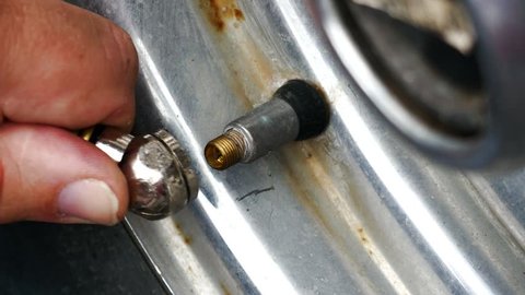 Compressed Air Fitting Held On The Valve Stem Of A Scratched Chrome Wheel