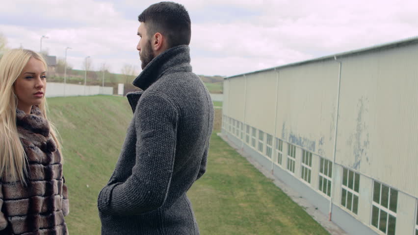 Beautiful young girl standing with a young dark-haired man in front and try to communicate. Dramatic scene between two people.