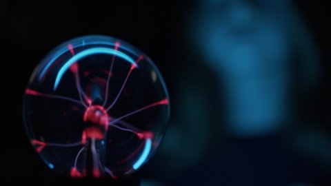 Lockdown Close Up Shot Of Girl'S Fingers Touching A Plasma Globe Emitting Red Lights From Inner Electrode And Touching Sphere Where Her Fingertips Are, A Rack Focus Reveals The Girl'S Face Watching