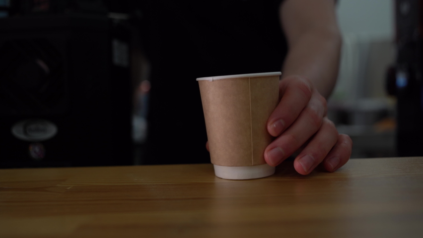 Barista moves on a wooden table Tea or coffee, espresso, latte, takeaway cappuccino. close-up Focused on the cup | Shutterstock HD Video #1065519514