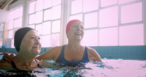 Two senior women embracing together in swimming indoor pool स्टॉक व्हिडिओ
