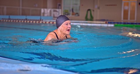 Senior woman swimming breaststroke style in indoor pool