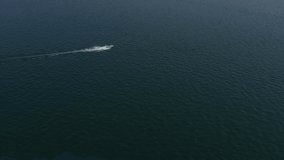 Large white boat fast movement on blue water, sun reflection in the water, view from the top to the boat 4k video. Drone view of a boat  the blue clear waters.	