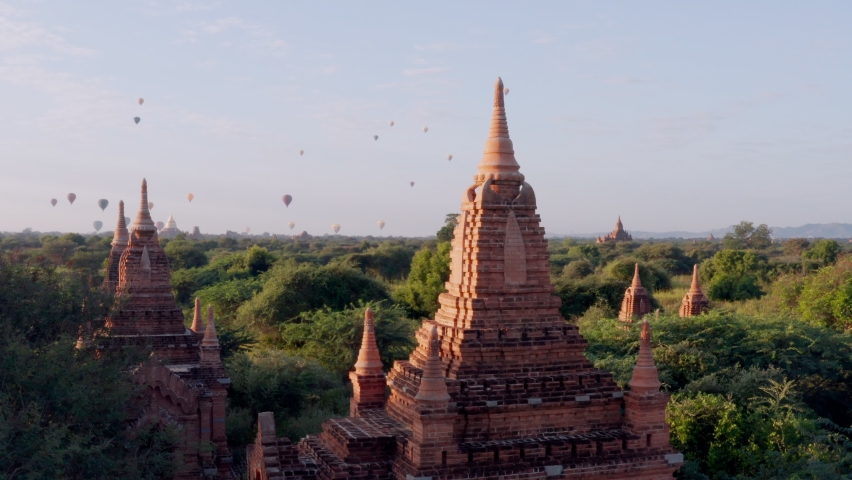 Stunning aerial drone shot of Bagan's temples and hot air balloons at sunrise. Balloons flying above ancient temples and pagodas in Bagan, Myanmar. Drone shot  Royalty-Free Stock Footage #1065523156