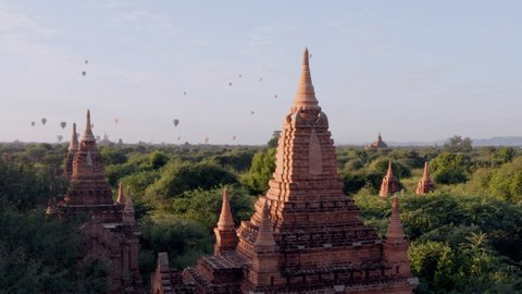 Stunning aerial drone shot of Bagan's temples and hot air balloons at sunrise. Balloons flying above ancient temples and pagodas in Bagan, Myanmar. Drone shot 