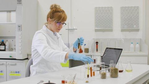 Close up of chemical scientists working with hemp CBD and CBDa oil in laboratory. She is using erlenmeyer flasks. Cannabis pharmaceutical healthcare concept.