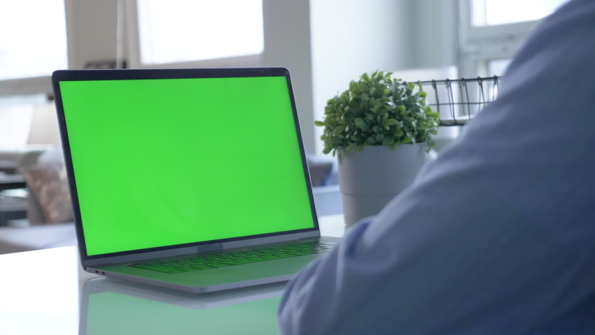 Male Office Worker at His Desk Works on a Laptop with Mock-up Green Screen. Over the Shoulder Close-up Footage. In the Background Creative Office Royalty-Free Stock Footage #1065525412