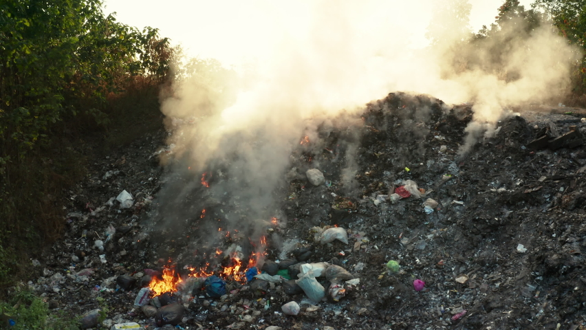 Garbage and fire burn in landfill. Also call trash, waste, rubbish. Destruction with combustion, heat, flame. Occurs smoke, toxic cause of air pollution, environmental damage and global warming. | Shutterstock HD Video #1065530206