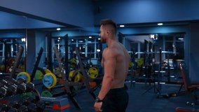 Strength workout. Determined fit man exercising with dumbbells pumping bicep muscles over gym background. Video from the back.