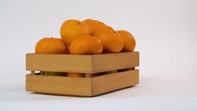 Fresh mandarin oranges fruit on white background. Mandarins in wooden box. Food Concept. Product for sale. Slider view. Copy space. High quality 4k video.
