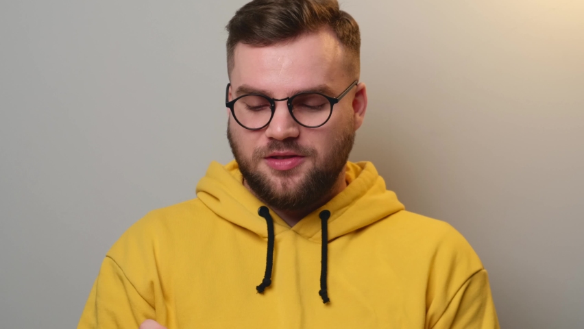 Bearded man is speaking at camera during an online lesson wearing glasses and looking in the copybook