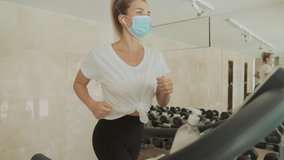 Sporty woman with face mask uses an exercise machine and hand sanitizer in the gym. Close-up. - Powered by Shutterstock - Get 15% off with code: PIKWIZARD15