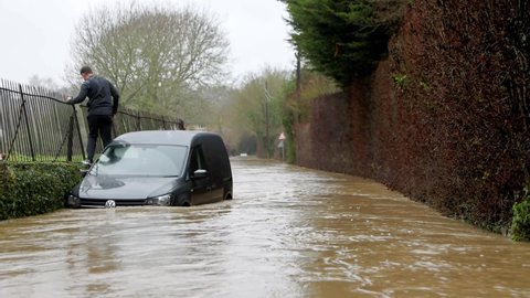 Much Hadham, Hertfordshire, UK. January 14th 2021. Man climbs out of his broken down van stranded on a flooded road.