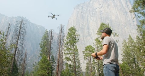 Yosemite National Park, USA. Man using copter or drone while shooting wild landscape. Caucasian cameraman shoots vistas in valley. High quality 4k footage