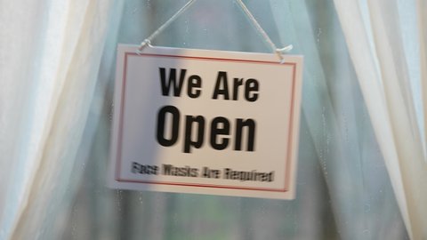 We are Open sign swinging in the window of store front display in business concept.