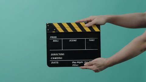 Movie Clapperboard. Film crew man hand hold and clap empty black and yellow stripe film slate in the frame. 3 2 1 Action. yellow and black color clapperboard on green blue background. Video production