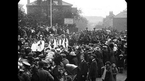 CIRCA 1912 - Crowds gather to watch an outdoor funeral procession in Hitchin, England.