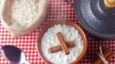 White corn cooked with milk known as canjica, canjicao or mungunza, typical dish of Brazilian gastronomy, in a rustic bowl, on wooden table
