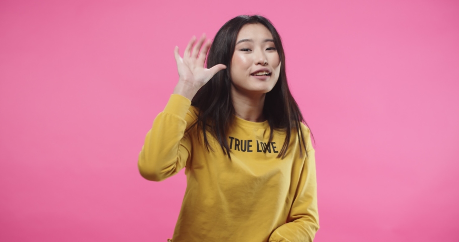 Portrait of Asian emotional cheerful young female with happy face standing isolated on pink wall background in studio making OK gesture, thumb up, approving something, cheering up | Shutterstock HD Video #1065563827