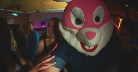 Group of friends at a party with one wearing a plush rabbit head